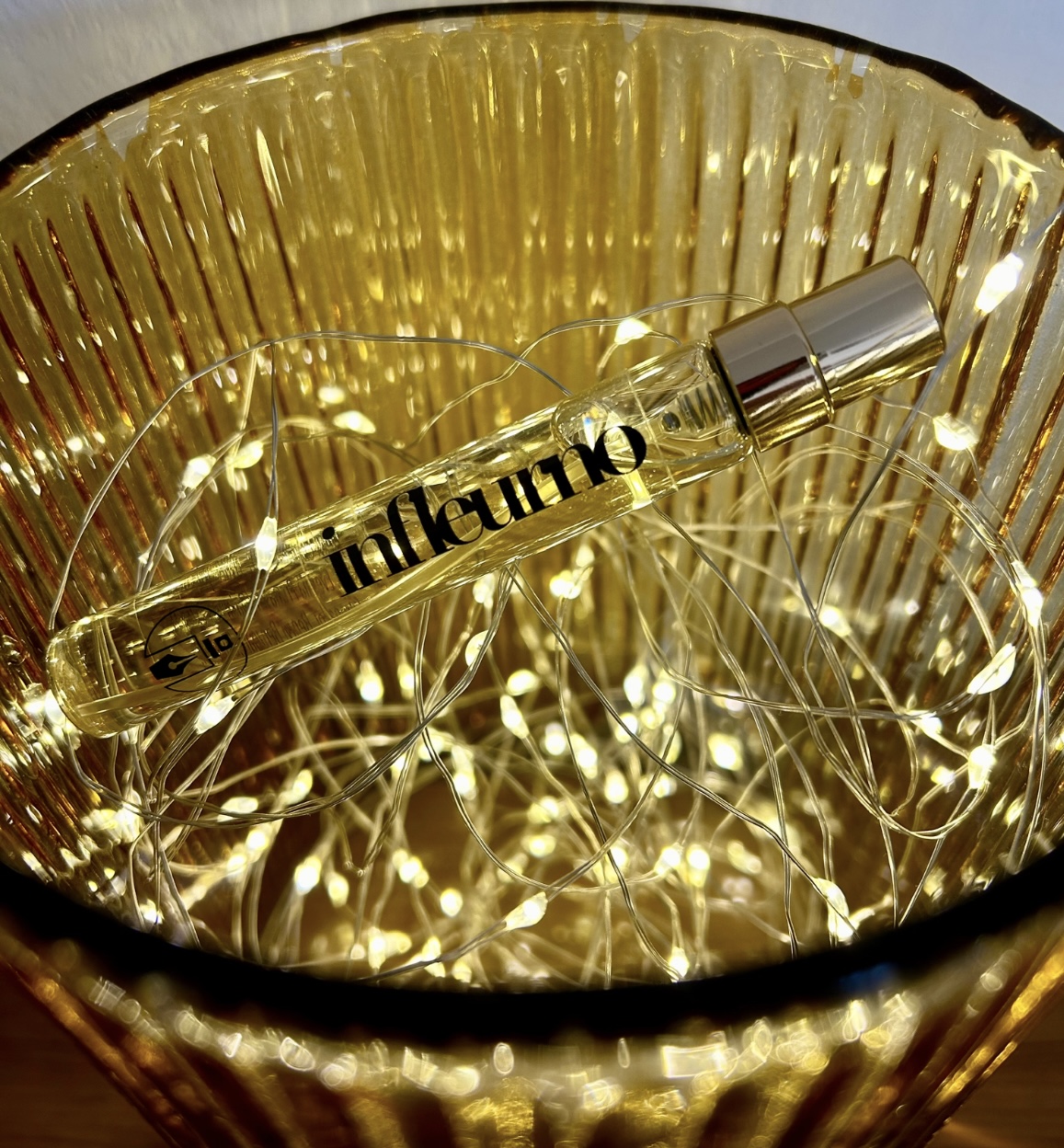 Travel vial of Infleurno perfume by Eau de Boujee in fairy lights.