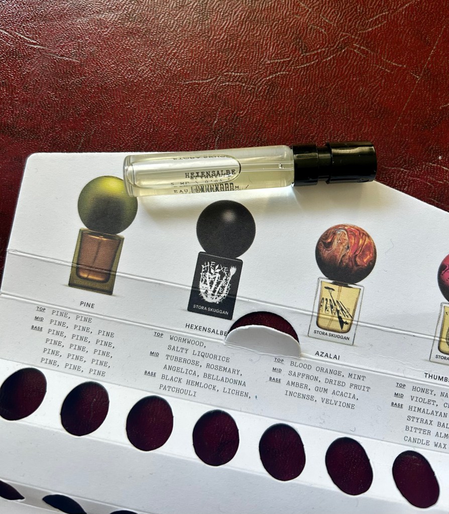 A glass vial of Hexensalbe perfume by Stora Skuggan is on the cardboard packaging of the brand's sample set.